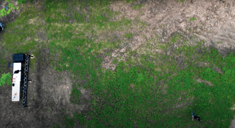 An aerial photo of a man walking many feet in front of a group of trail cameras
