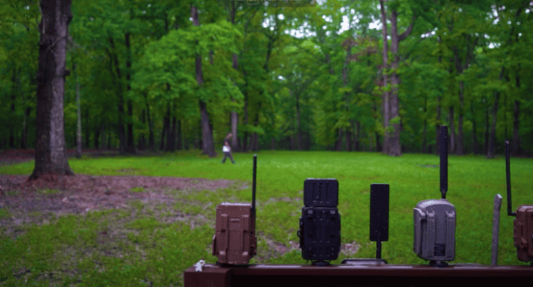 A man walking yards in front of a group of trail cameras